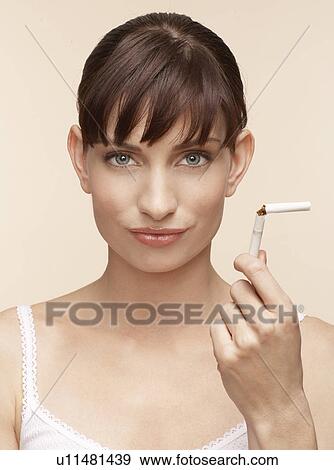 Stock Photo - Mid adult woman holding broken cigarette. Fotosearch