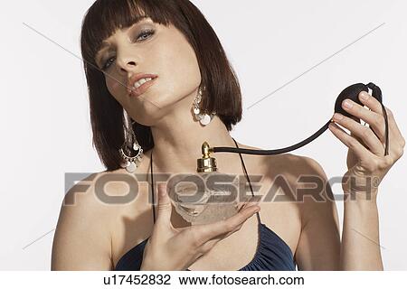 Mid adult woman spraying on perfume View Large Photo Image Stock Image - Mid adult woman spraying on perfume. Fotosearch