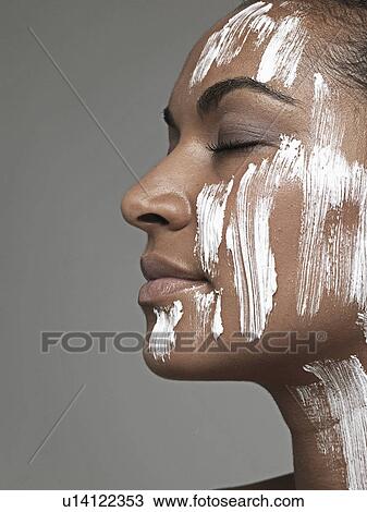 Stock Image - Moisturizer on young woman's face. Fotosearch