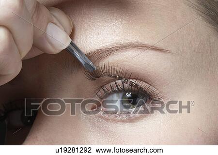 Stock Image - Woman attaching fake eyelashes, close-up. Fotosearch