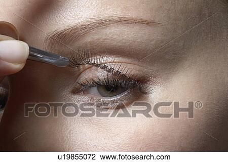Stock Image - Woman attaching fake eyelashes, close-up. Fotosearch
