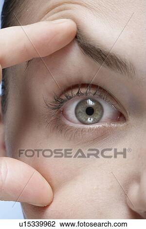 Stock Image - Woman holding her eye open, close-up. Fotosearch