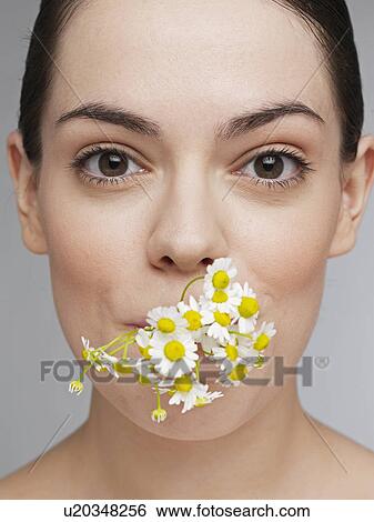 Young woman holding flowers in mouth View Large Photo Image Stock Photograph - Young woman holding flowers in mouth. Fotosearch