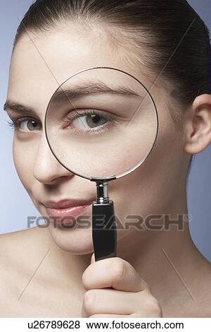 Stock Photo - Young woman looking through magnifying glass. Fotosearch