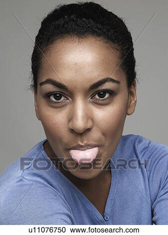 Stock Image - Young woman sticking out tongue. Fotosearch