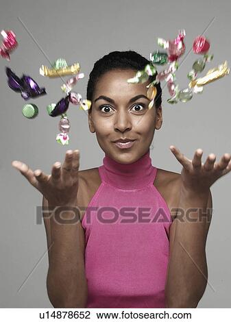 Stock Image - Young woman throwing candies in air. Fotosearch