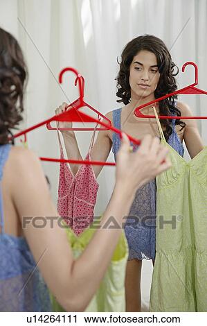 Stock Image - Young Woman Choosing Dresses. Fotosearch