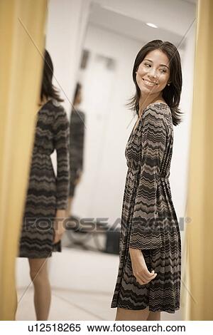 Stock Photography - Young woman trying dress on. Fotosearch
