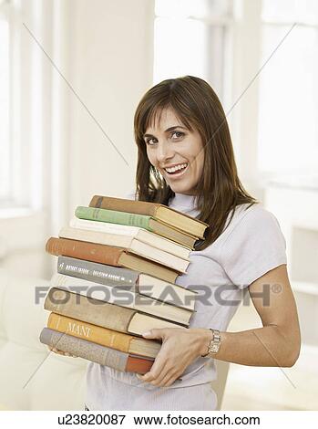 Stock Photo - Mid-Adult Woman Carrying Stack of Books. Fotosearch