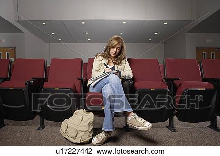 Stock Image - Student making notes in lecture theater. Fotosearch