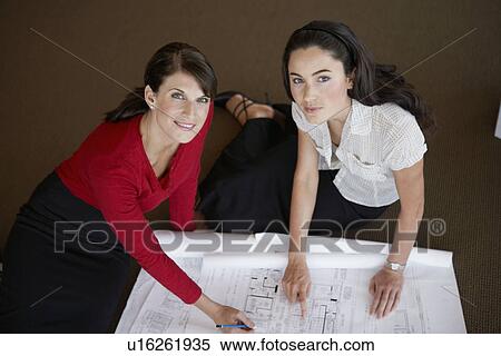 Two businesswomen examining blueprints (portrait, high angle view) View Large Photo Image Stock Photography - Two businesswomen examining blueprints (portrait, high angle view). Fotosearch