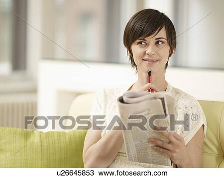 Stock Image - Young Woman Doing Crossword Puzzle. Fotosearch