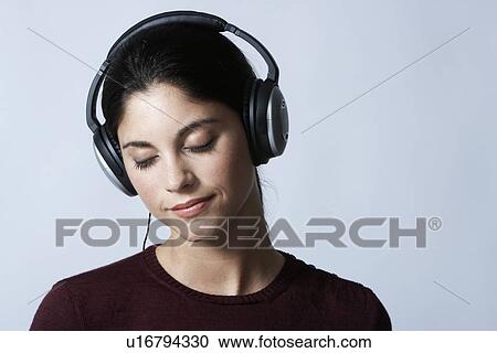 Young woman listening to headphones with eyes closed View Large Photo Image Stock Image - Young woman listening to headphones with eyes closed. Fotosearch