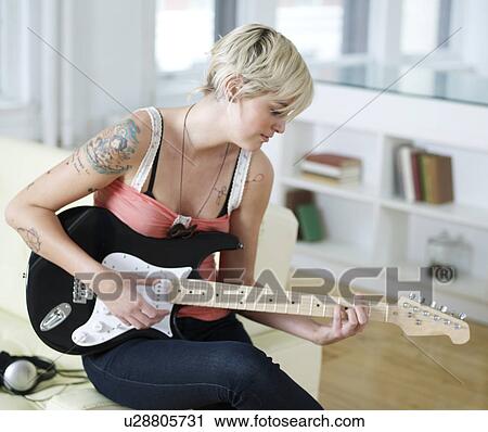 Stock Image - Young Woman Playing Electric Guitar. Fotosearch