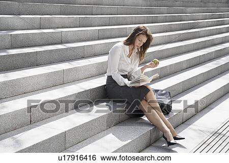 Young woman reading and eating on steps View Large Photo Image Stock Photograph - Young woman reading and eating on steps. Fotosearch