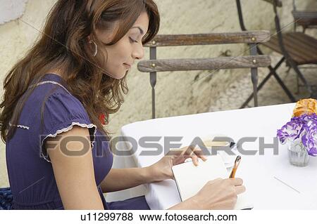 Stock Photo - Young woman writing on note book. Fotosearch