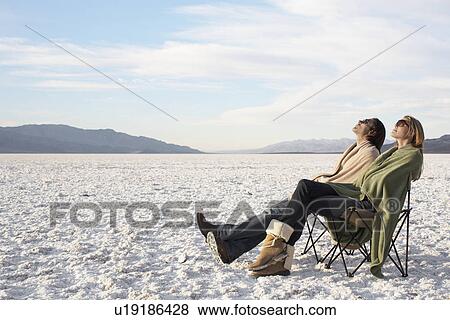Couple sitting on sun loungers in desert View Large Photo Image Stock Photo - Couple sitting on sun loungers in desert. Fotosearch