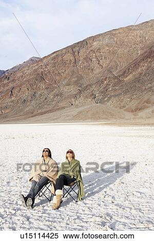 Couple sitting on sun loungers in desert (high angle view) View Large Photo Image Stock Photography - Couple sitting on sun loungers in desert (high angle view). Fotosearch