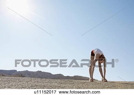 Stock Photo - Female runner stretching (low angle view). Fotosearch