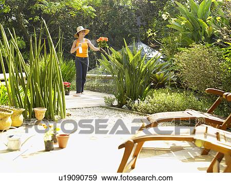 Woman watering plants in garden View Large Photo Image Stock Photo - Woman watering plants in garden. Fotosearch