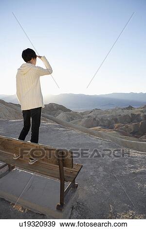 Young woman standing on bench and looking at view in desert, Death Valley, California, USA View Large Photo Image Stock Photo - Young woman standing on bench and looking at view in desert, Death Valley, California, USA. Fotosearch