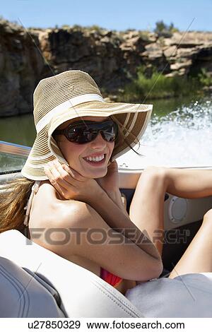 Young woman wearing hat and sunglasses on motorboat View Large Photo Image Stock Photo - Young woman wearing hat and sunglasses on motorboat. Fotosearch