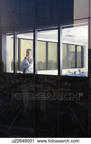 Businessman looking through office window (exterior view) View Large Photo Image Stock Image - Businessman looking through office window (exterior view). Fotosearch