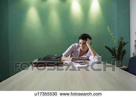 Stock Image - Businesswoman making notes in boardroom. Fotosearch