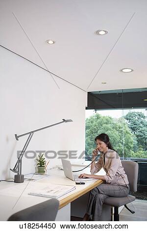 Young businesswoman with laptop talking on the phone View Large Photo Image Stock Image - Young businesswoman with laptop talking on the phone. Fotosearch