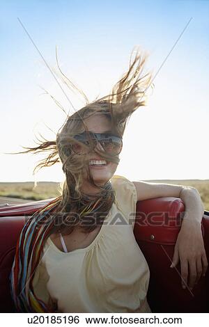 Young woman with wind swept hair in convertible View Large Photo Image Stock Photograph - Young woman with wind swept hair in convertible. Fotosearch