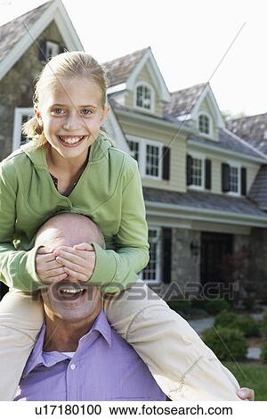 Stock Image - Daughter (10-11) sitting on fathers shoulders and covering his eyes, Chatham, New Jersey, USA. Fotosearch