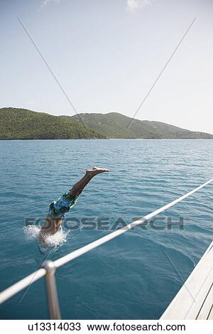 Mid adult man jumping from sailboat, St. John, US Virgin Islands, USA View Large Photo Image Stock Image - Mid adult man jumping from sailboat, St. John, US Virgin Islands, USA. Fotosearch