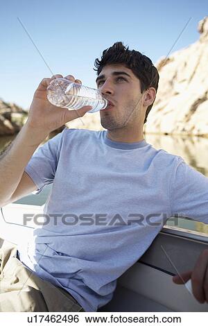 Stock Photograph - Young man drinking water in boat. Fotosearch
