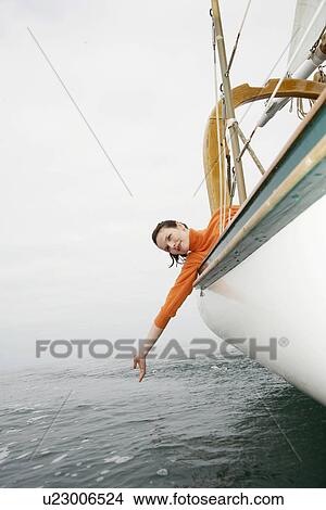 Young woman leaning over side (low angle view) View Large Photo Image Picture - Young woman leaning over side (low angle view). Fotosearch