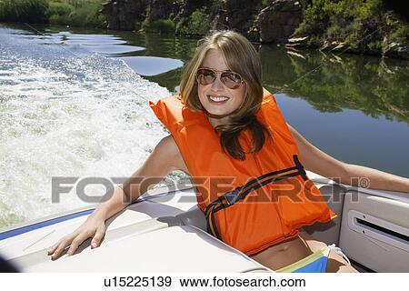 Stock Photo - Young woman wearing life jacket in motorboat. Fotosearch