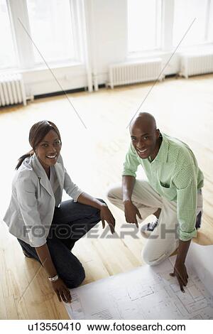 Architects examining blueprints on wooden floor (high angle view) View Large Photo Image Stock Image - Architects examining blueprints on wooden floor (high angle view). Fotosearch
