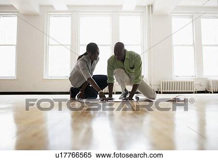 Stock Photography - Architects looking at blueprints in empty room. Fotosearch