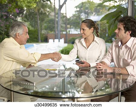 Businesspeople shaking hands at table View Large Photo Image Stock Photography - Businesspeople shaking hands at table. Fotosearch