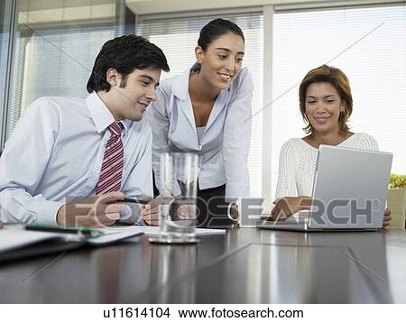 Picture - Businesspeople using laptop computer in meeting. Fotosearch