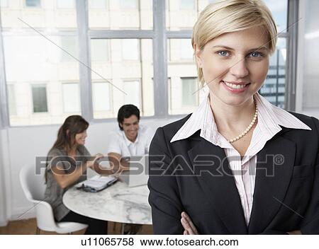 Female manager, colleagues using laptop in background (portrait) View Large Photo Image Stock Photo - Female manager, colleagues using laptop in background (portrait). Fotosearch