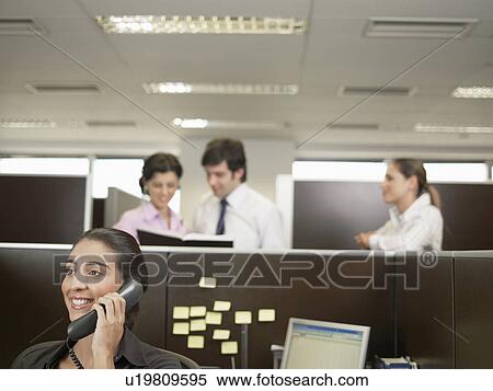 Office worker on phone, co-workers planning in background View Large Photo Image Stock Photography - Office worker on phone, co-workers planning in background. Fotosearch
