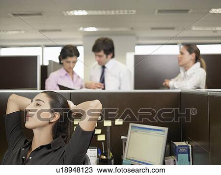 Stock Image - Office worker resting, co-workers planning in background. Fotosearch