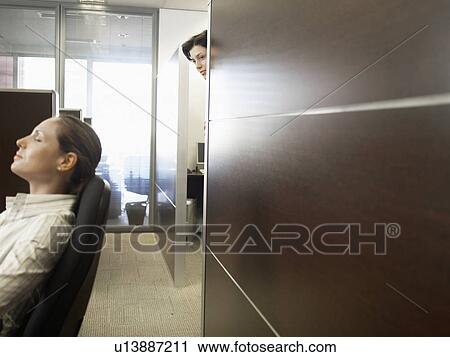 Stock Image - Office worker watching co-worker sleeping. Fotosearch