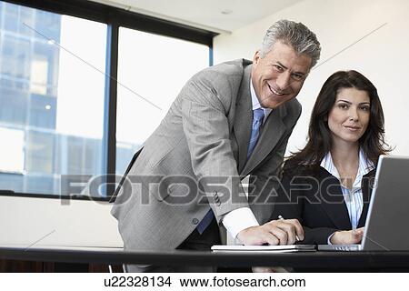 Picture - Two businesspeople working on laptop. Fotosearch