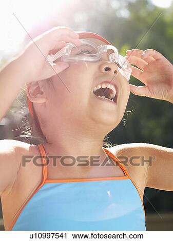 Stock Image - Girl adjusting swimming goggles (lens flare). Fotosearch