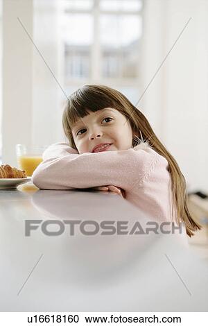Stock Image - Girl in dressing gown having breakfast. Fotosearch