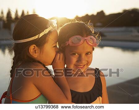 Stock Photo - Girls sharing secret by swimming pool. Fotosearch