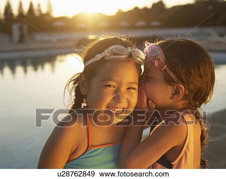 Stock Photo - Girls sharing secret by swimming pool. Fotosearch