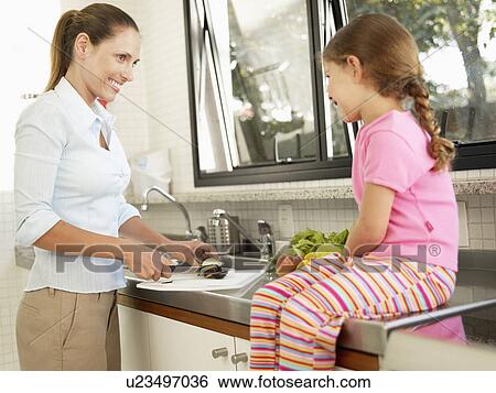 Stock Photograph - Mother and daughter cutting vegetables. Fotosearch