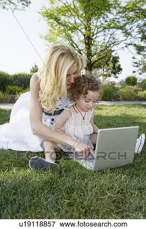 Stock Photo - Mother and daughter using laptop in park. Fotosearch